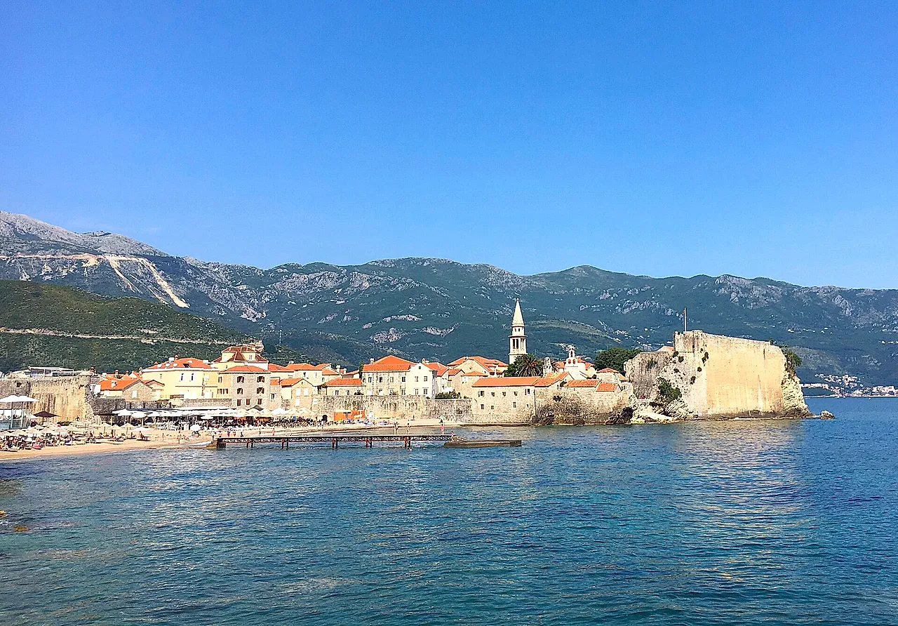 Die Altstadt von Budva mit der Zitadelle auf der Landzunge, türkisfarbenes Meer und Berge
