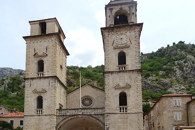 The twin bell towers and façade of the Cathedral of St Tryphon in Kotor, with the mountain slope behind